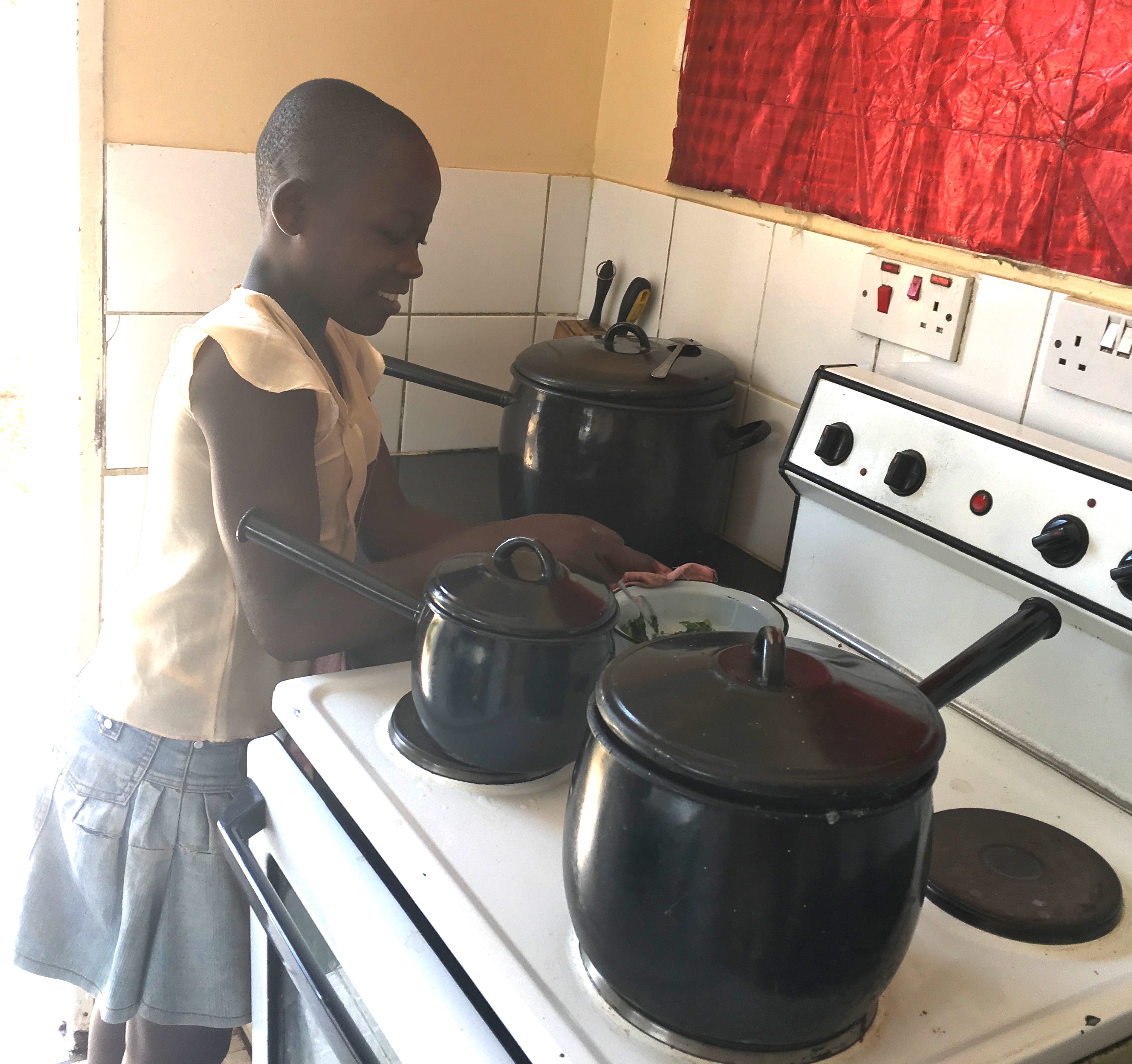 A child, new to the home, helps cook the dinner as she waits for a placement in school